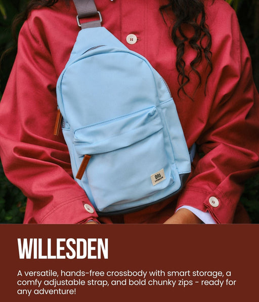 Person wearing a blue crossbody bag with promotional text for Willesden bag by Ori London.