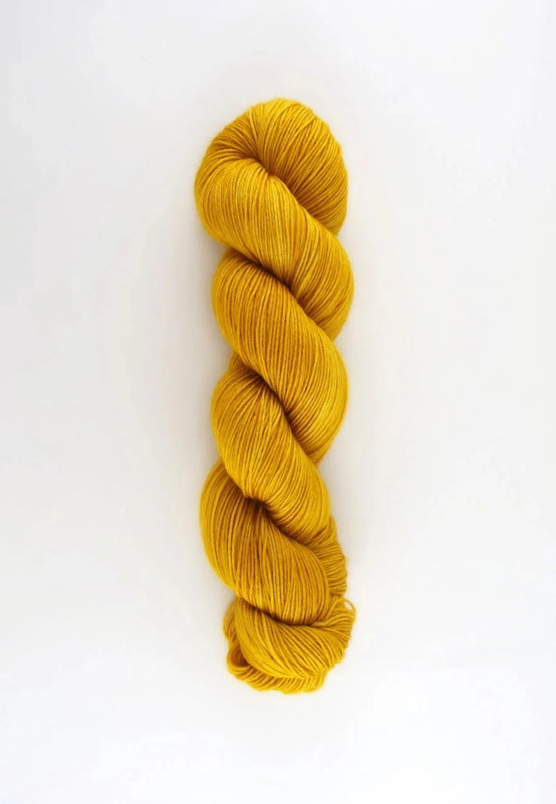 Mustard yellow skein of yarn on a white background