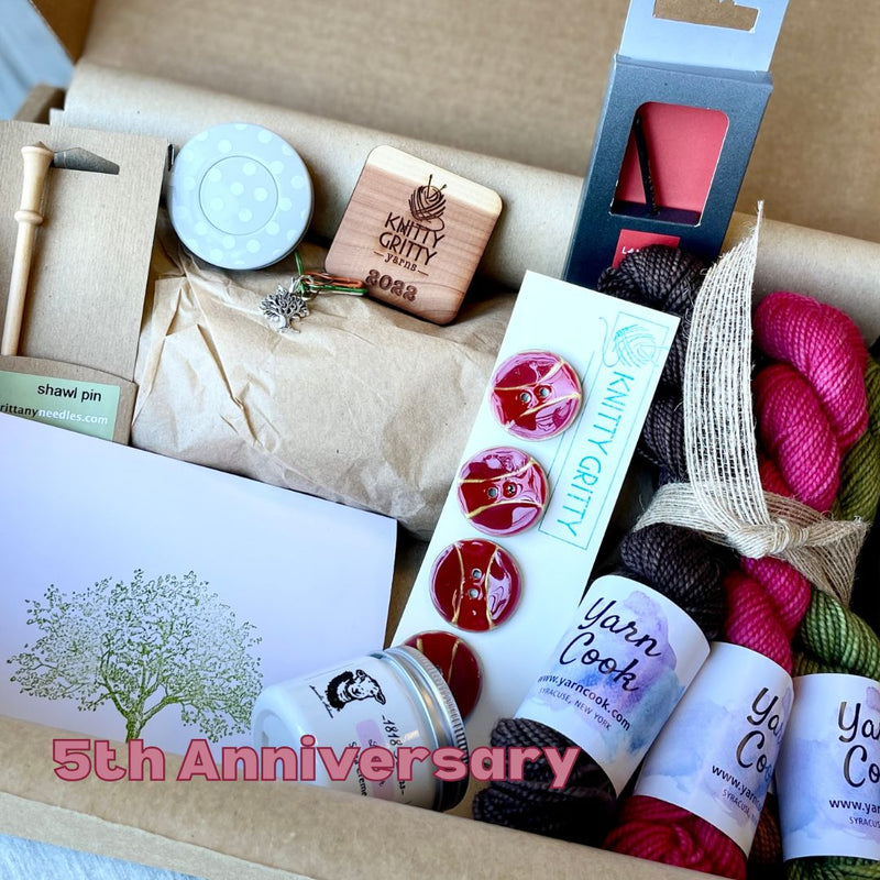 Knitting supplies including yarn, needles, and a 'Knitty Gritty' box in a cardboard box.