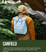 Person wearing a light blue backpack with green foliage in the background, featuring Canfield and Ori London branding.