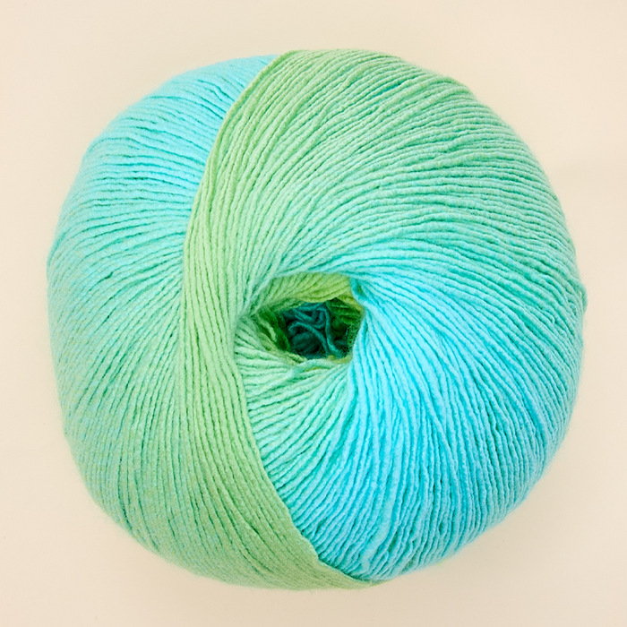 Ball of yarn with a gradient from green to blue on a beige background
