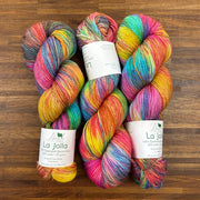 Four skeins of colorful yarn with 'La Jolla' labels on a wooden surface