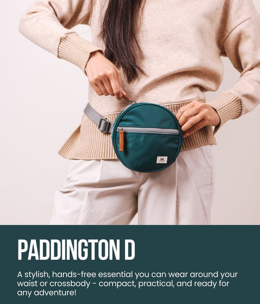 Person wearing a teal waist bag with 'Paddington D' branding on a light background