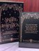 Two black books with gold text and decorative elements on a wooden surface.