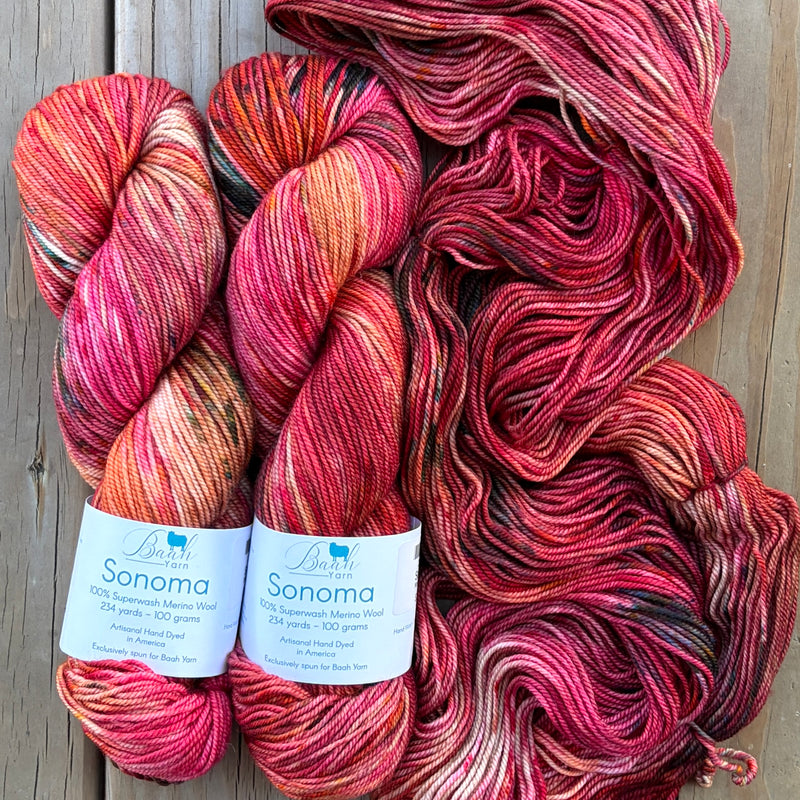 Three skeins of multicolored yarn with 'Sonoma' labels on a wooden surface