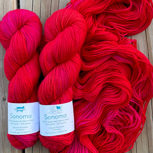 Red yarn skeins with 'Sonoma' labels on a wooden surface