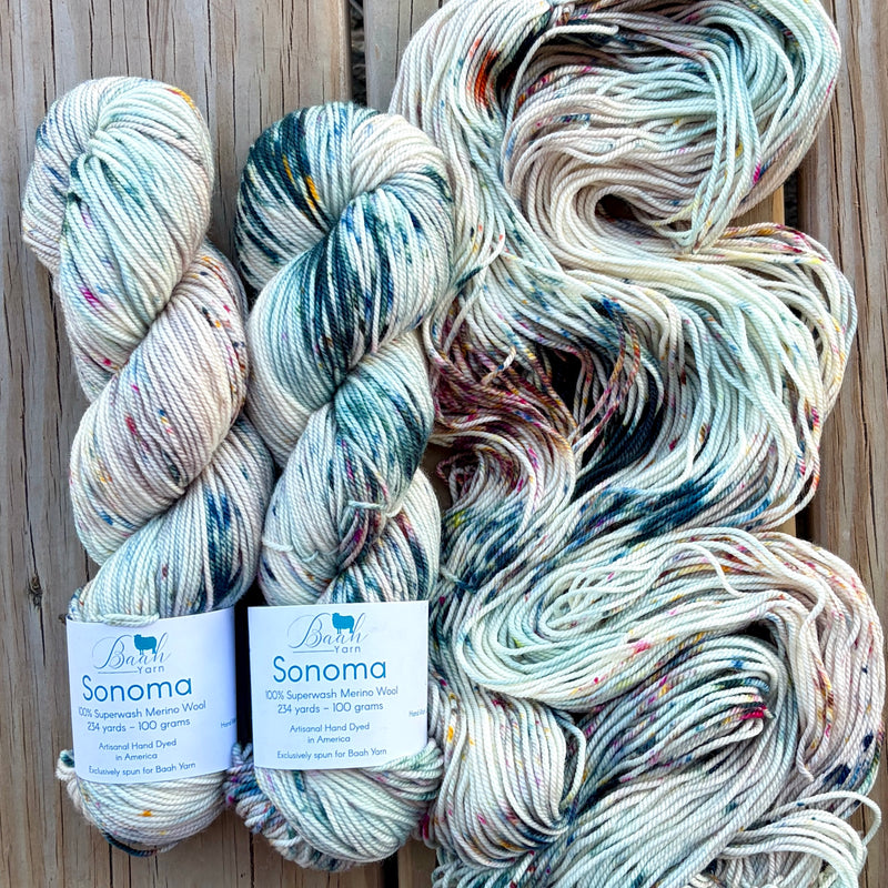 Three skeins of yarn with 'Sonoma' labels on a wooden background