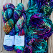 Two skeins of colorful yarn with labels on a wooden surface