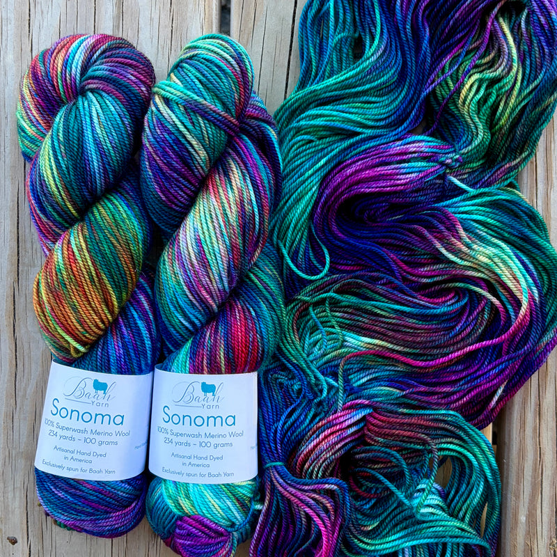 Two skeins of colorful yarn with labels on a wooden surface