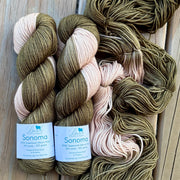 Three skeins of yarn with labels on a wooden surface