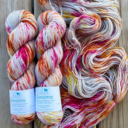 Three skeins of multicolored yarn with labels on a wooden surface