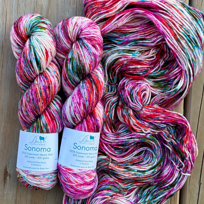 Two skeins of multicolored yarn with labels on a wooden surface
