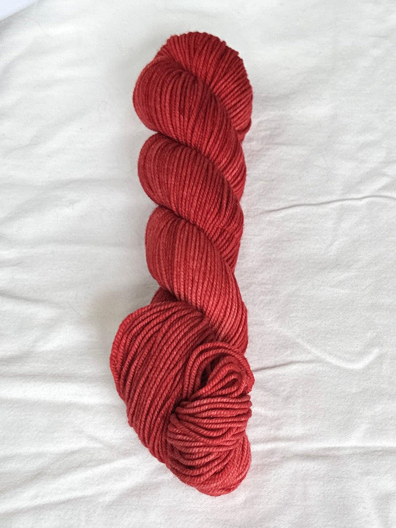 Red skein of yarn on a white fabric background
