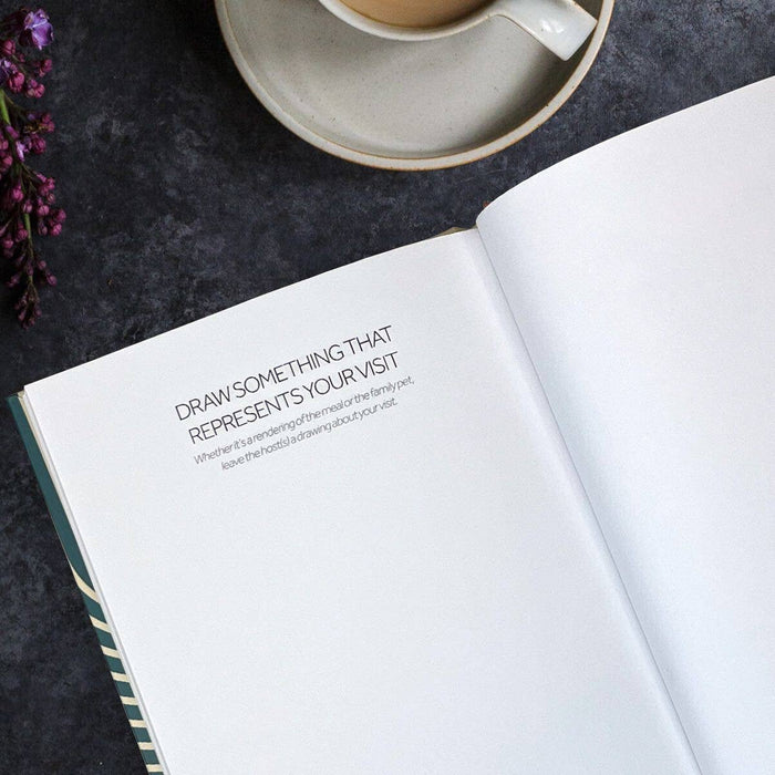 Open book with text on a dark surface with a cup and flowers.