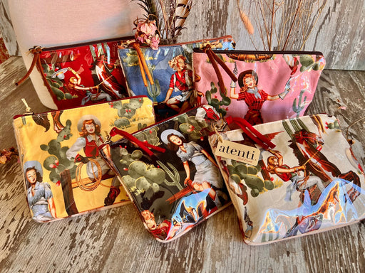 Set of six colorful pouches with vintage-cowgirl designs on a wooden surface