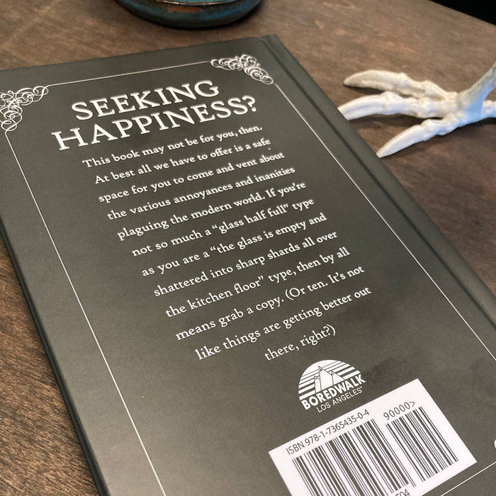 Back of Book titled 'Seeking Happiness?' with text and a Boredwalk Los Angeles logo on a wooden surface.
