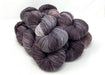 Three skeins of purple and gray yarn on a white background
