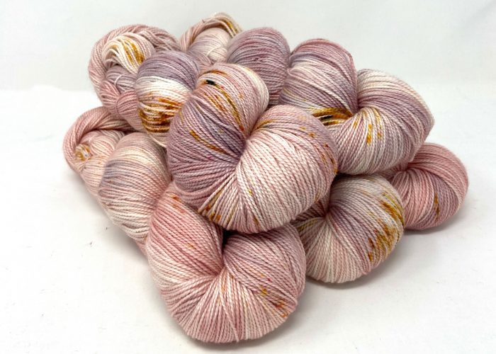 Pink and gold skeins of yarn on a white background