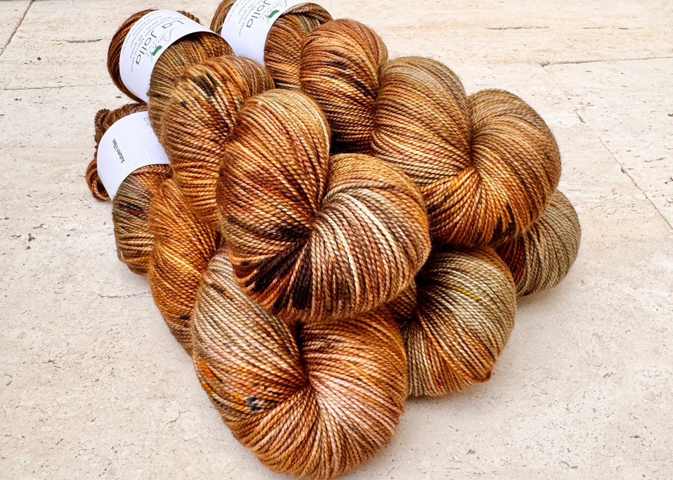 Brown skeins of yarn on a light wooden surface