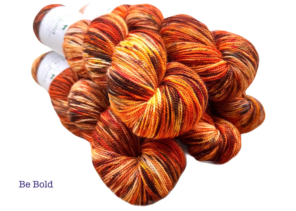 Multicolored yarn skeins with 'Be Bold' text on a white background