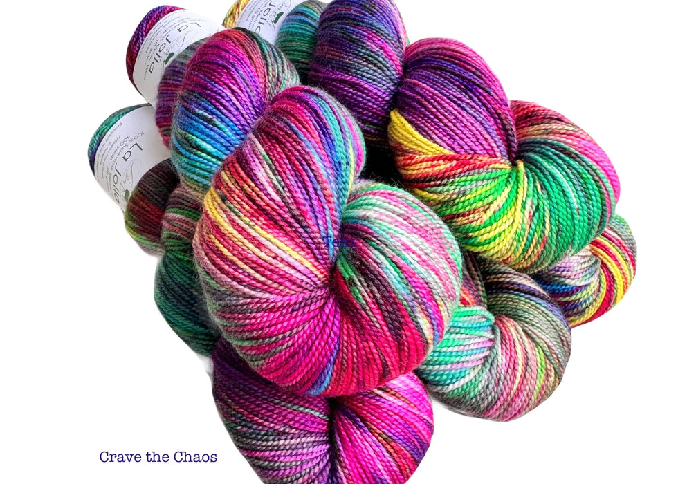 Colorful skeins of yarn with the words "Crave the Chaos" on a white background