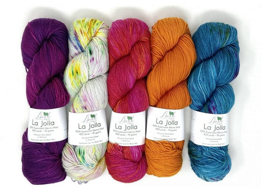 A collection of hand-dyed fingering weight yarn skeins in various colors, labeled 'La Jolla' by Baah Yarn.