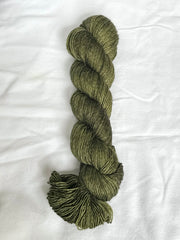 Green skein of yarn on a white fabric background