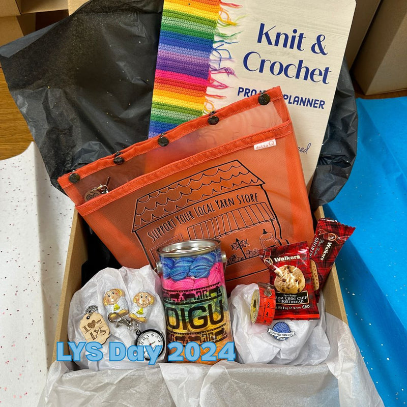 Box containing various items with a 'Knit & Crochet' planner and colorful bag.