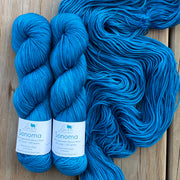 Two skeins of blue yarn with labels on a wooden surface