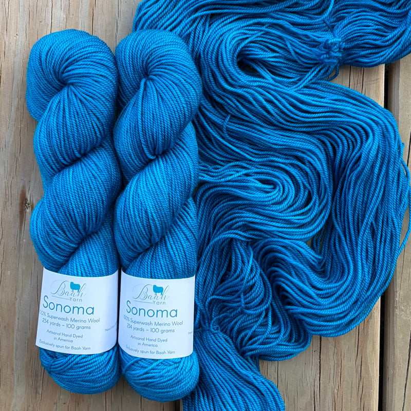 Two skeins of blue yarn with labels on a wooden surface