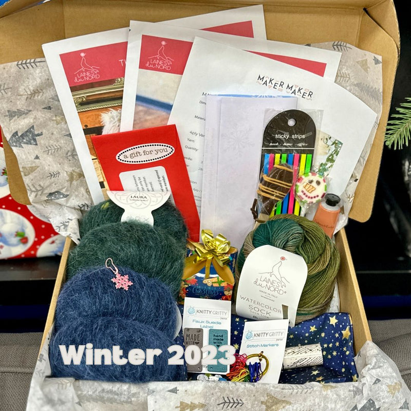 Box containing yarn, knitting needles, and related items with 'Winter 2023' text.